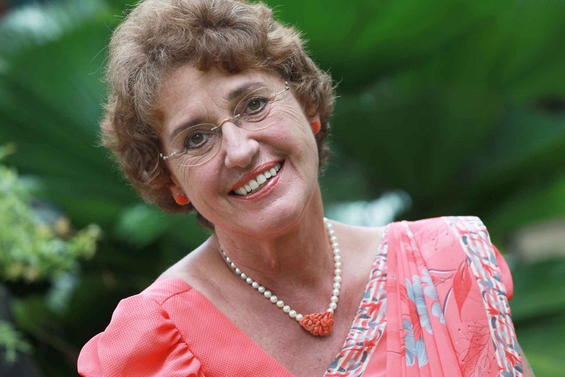Ursula Beier lächelnd, im Garten mit tropischer Bepflanzung